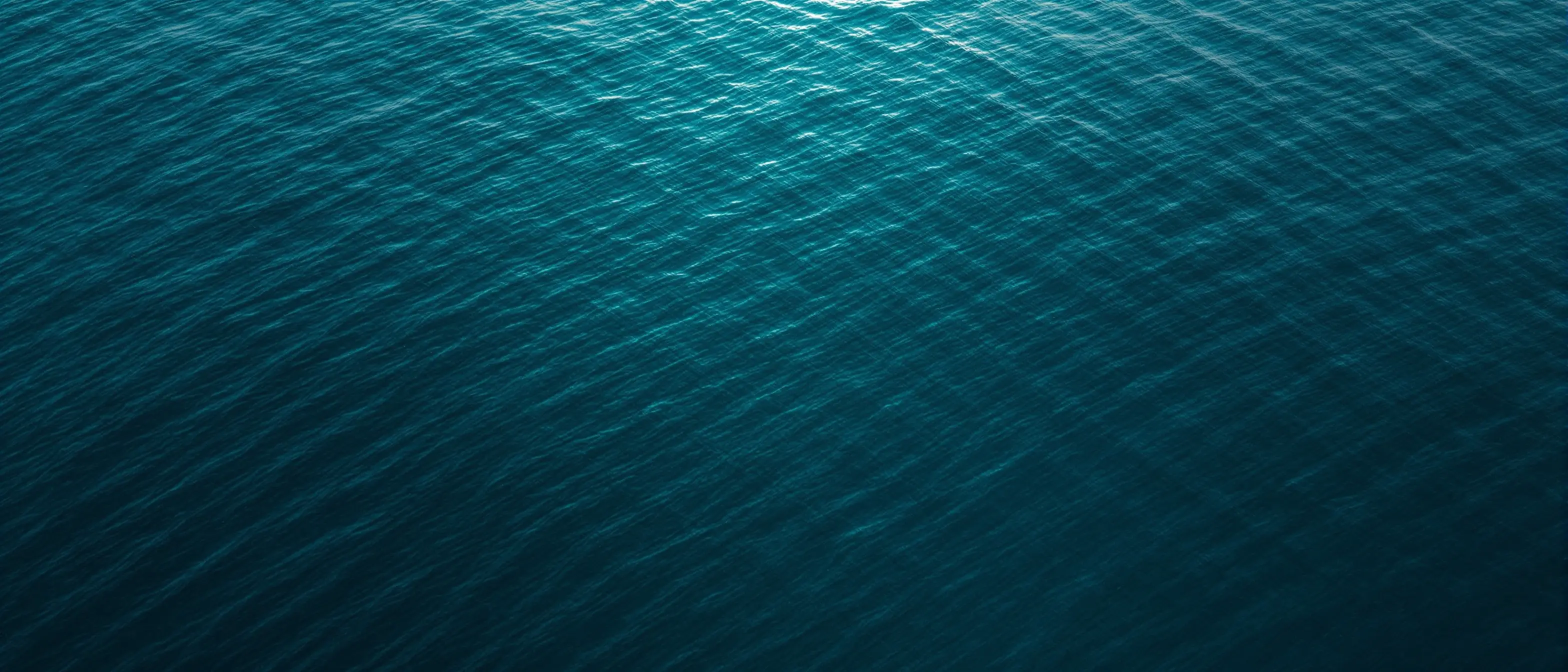Start Your GLP-1 Weight Loss Journey: Surfbound Health Aerial view of calm deep teal ocean water at dusk
