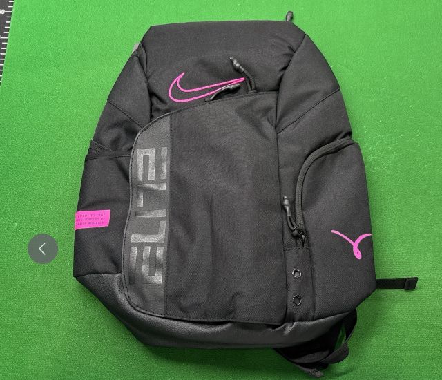 Mochila negra con detalles rosas, letras ELITE grises y tiradores visibles sobre una base verde Mochila negra con detalles rosas, letras ELITE grises y tiradores visibles sobre una base verde