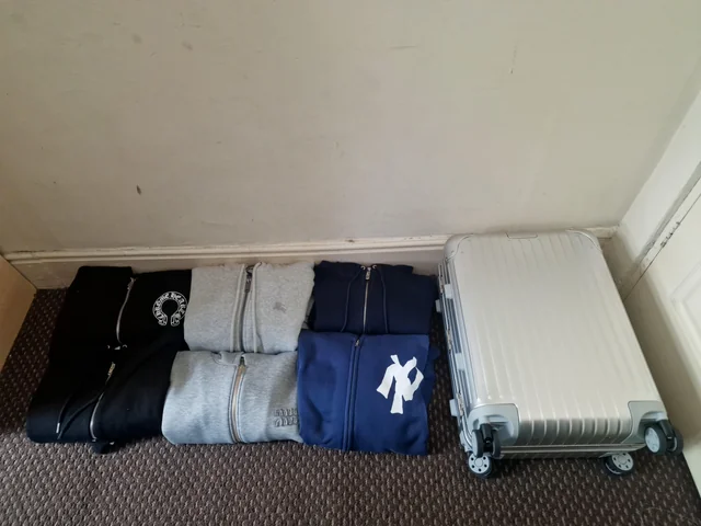 Six folded zip-front tops beside a silver-coloured suitcase in the source author’s haul photograph. Six folded zip-front tops beside a silver-coloured suitcase in the source author’s haul photograph.